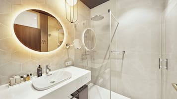 Casa de banho moderna com lavatório branco, espelho grande e cabine de duche em vidro.