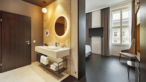 Un baño moderno con lavamanos doble, un espejo con luz circular y un perchero para toallas.