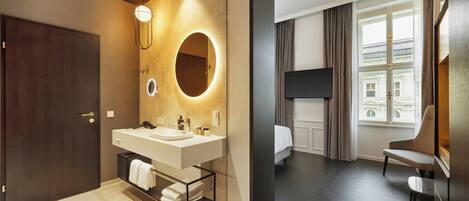 Un baño moderno con lavamanos doble, un espejo con luz circular y un perchero para toallas.