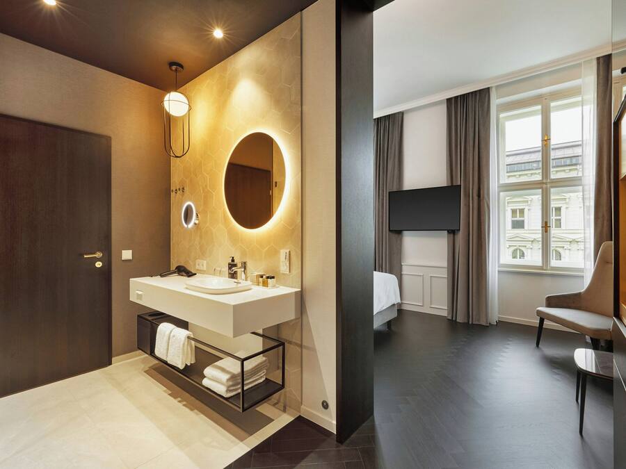 Un baño moderno con lavamanos doble, un espejo con luz circular y un perchero para toallas.