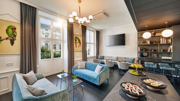 A modern living room with a sofa, armchairs, a dining area, and a bookshelf.