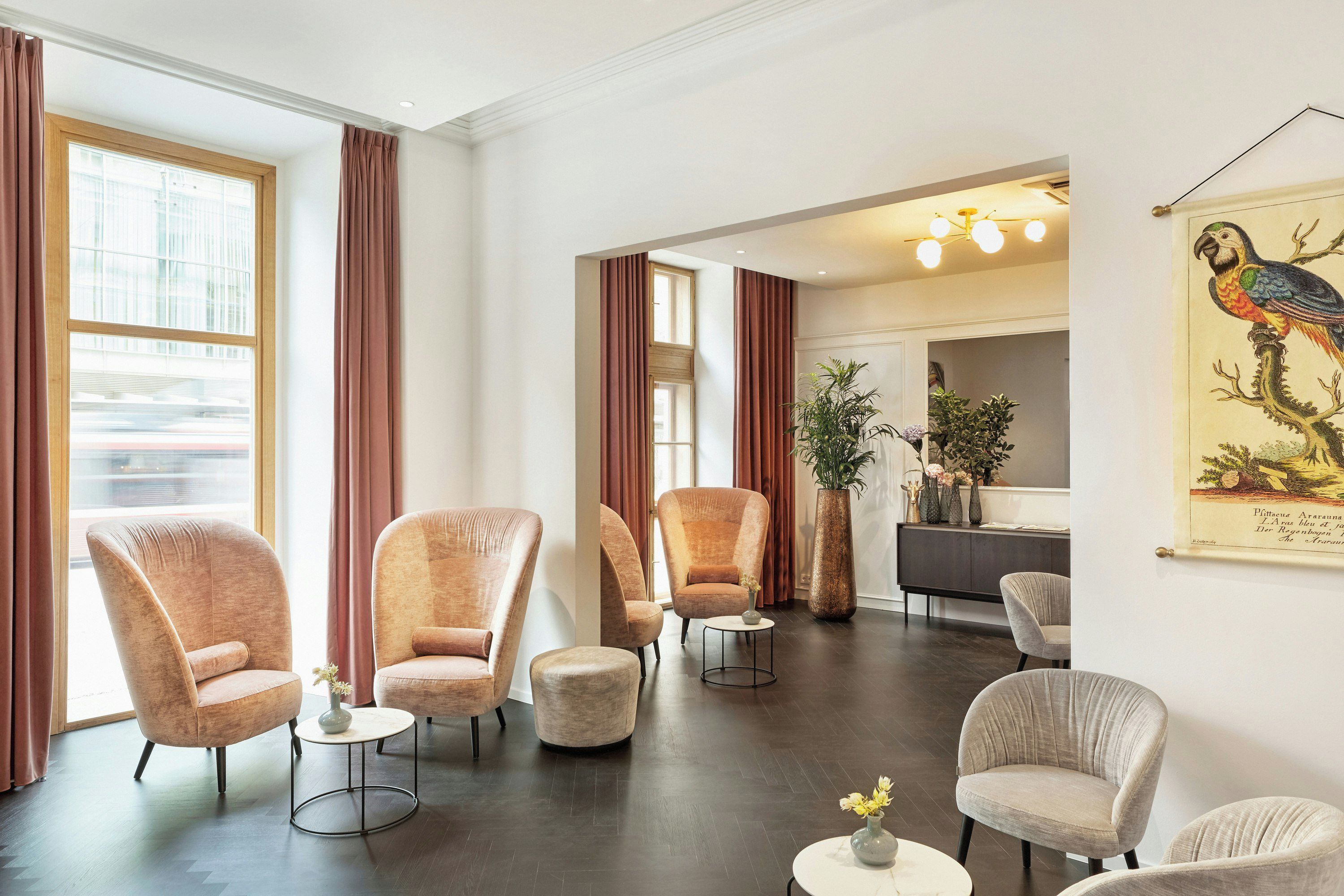 Ein moderner Lounge-Bereich mit bequemen Ohrensesseln, einem runden Couchtisch und einer großen Pflanze in einem Topf.