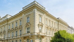 Un edificio grande e histórico con arquitectura clásica, con múltiples ventanas y detalles ornamentados.
