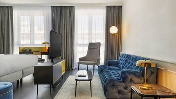 Une chambre d’hôtel comprenant un lit, un canapé, un bureau avec une télévision, une chaise et une lampe.