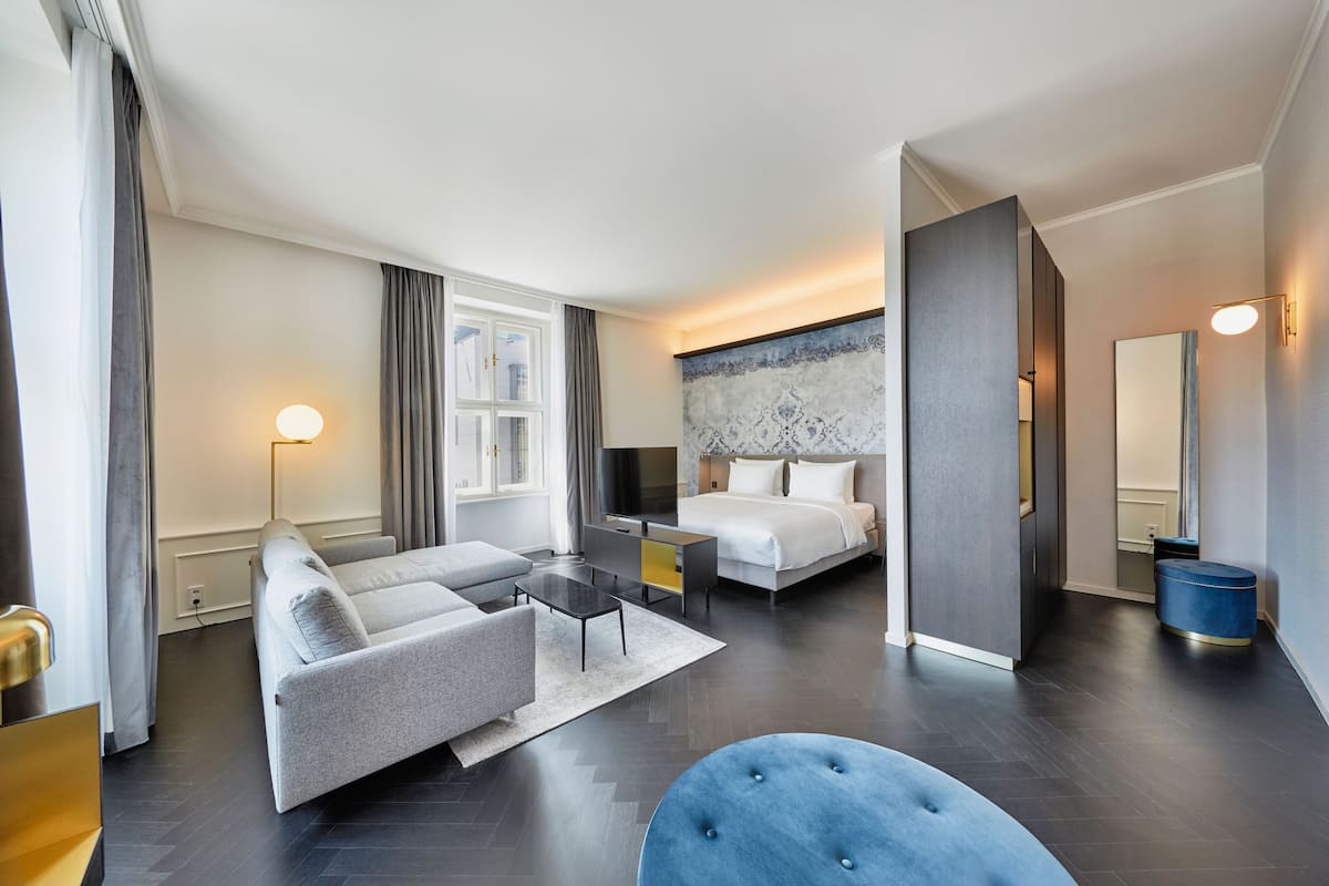 Una habitación de hotel moderna con sofá, cama, escritorio y un espejo grande.