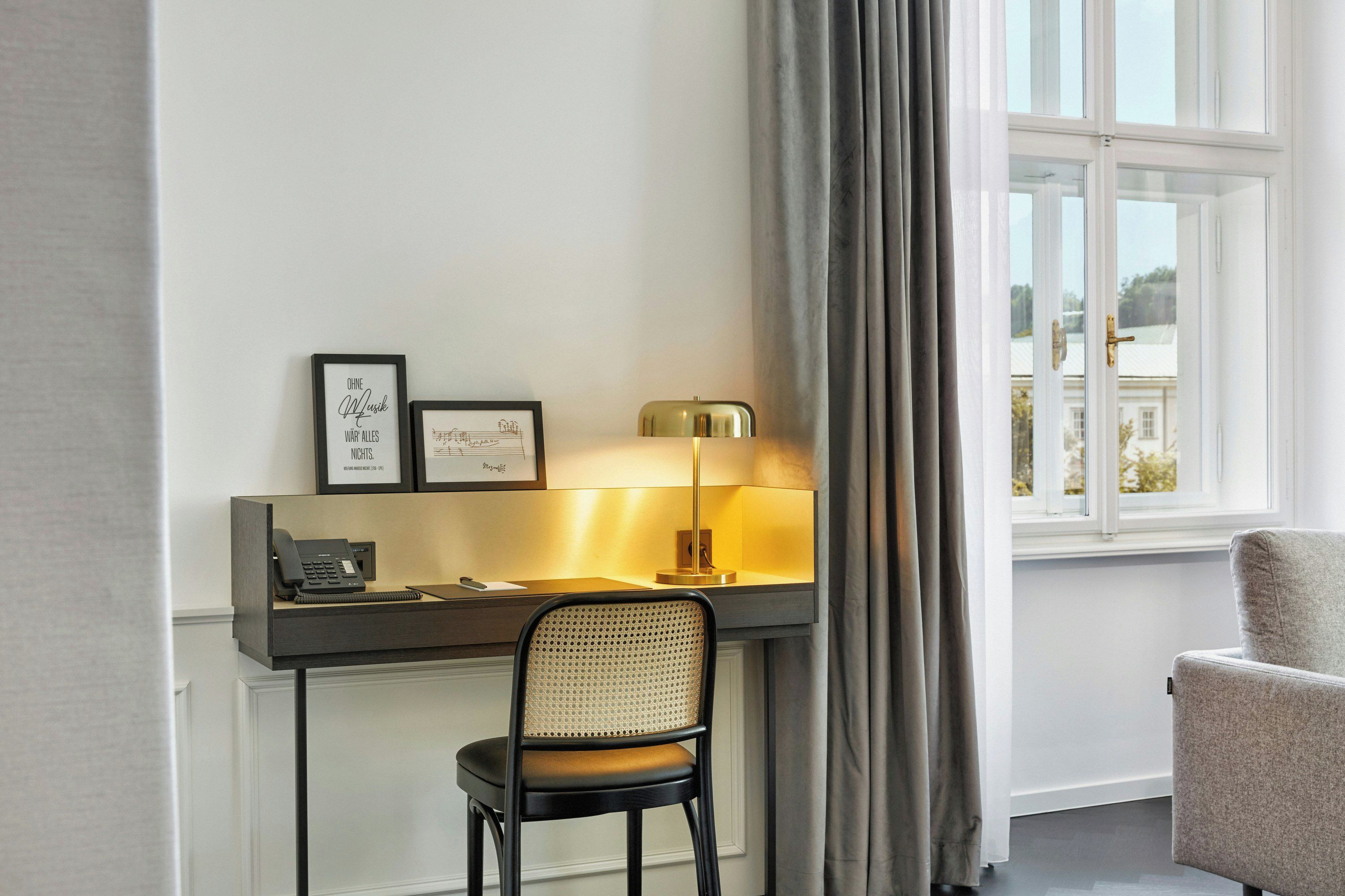 Une chambre d’hôtel équipée d’un bureau, d’une chaise, d’une lampe et offrant une vue sur l’extérieur par une fenêtre.