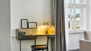 Une chambre d’hôtel équipée d’un bureau, d’une chaise, d’une lampe et offrant une vue sur l’extérieur par une fenêtre.