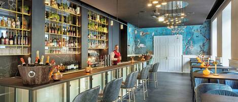A bar area with a bartender, shelves of liquor, and seating.