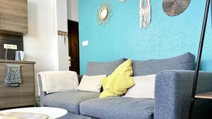 Una sala de estar moderna con un sofá gris, una mesa redonda de centro y decoración en la pared.