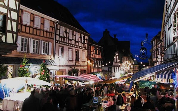Une rue de marché animée, bordée de bâtiments traditionnels à colombages et décorée de manière festive.