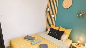 A bedroom with a bed, bedside table, wall-mounted plants, and a hanging light fixture.