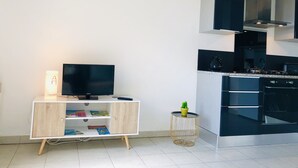 A modern kitchen with black cabinets, a built-in oven, and a TV on a wooden cabinet. - Magnificent location with breathtaking views of Collioure and the sea (Collioure)