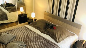 A neatly made bed with a striped blanket, pillows, and a rose. There are bedside tables with lamps, a mirror, and a striped wall. - Magnificent location with breathtaking views of Collioure and the sea (Collioure)