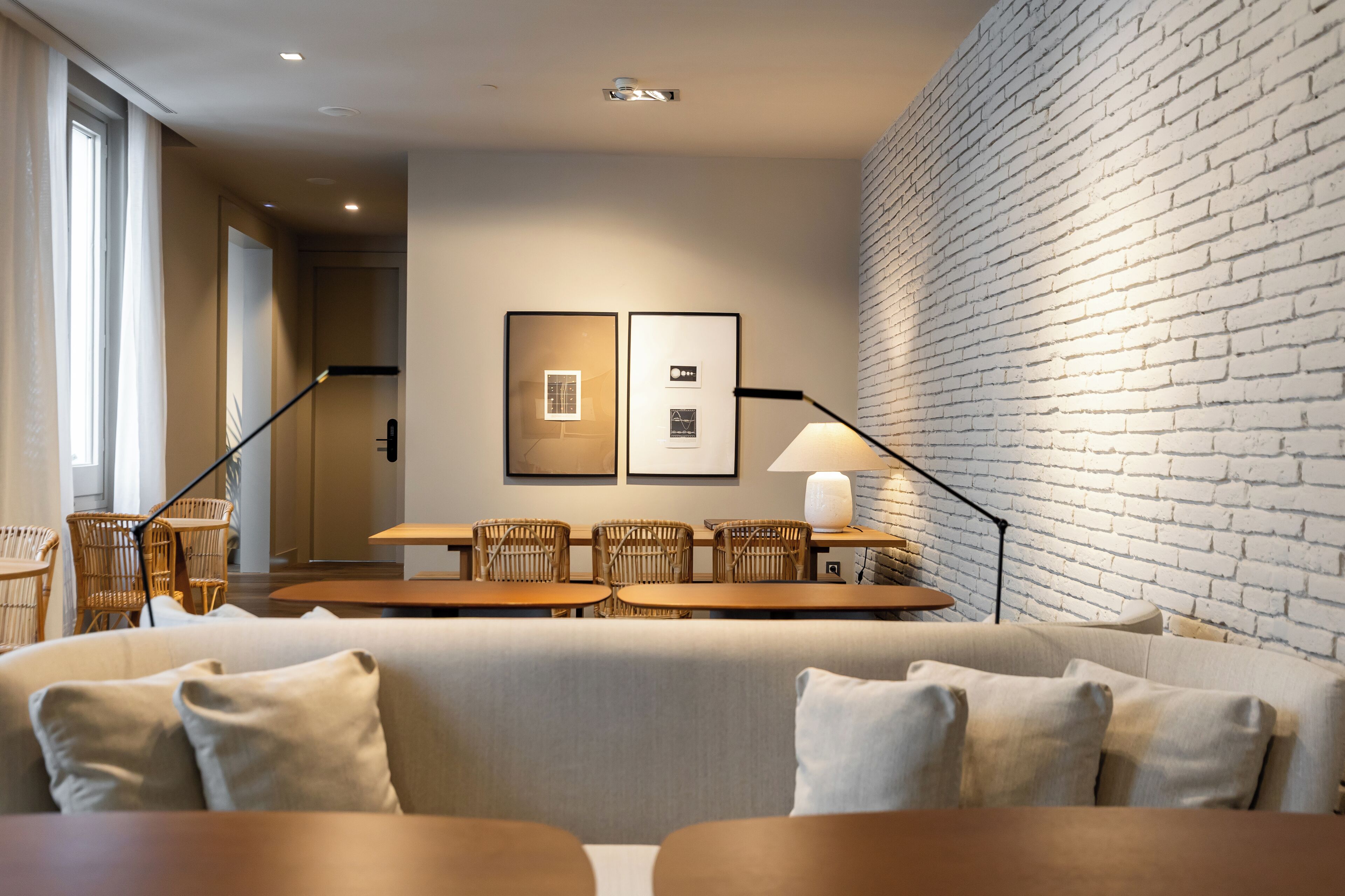 Un moderno salón con pared de ladrillo, un sofá, una mesa de comedor con sillas y cuadros en la pared.