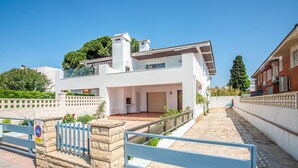 A modern two-story house with a balcony, a stone wall, and a blue gate. - See front apartment for 6 (Cambrils)