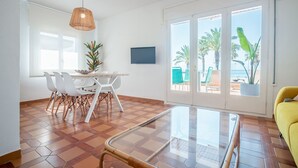A spacious living area with a dining table, chairs, a glass coffee table, and a yellow sofa. - See front apartment for 6 (Cambrils)