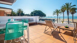 A terrace with a table and chairs, a sofa, and a view of the beach and palm trees. - See front apartment for 6 (Cambrils)