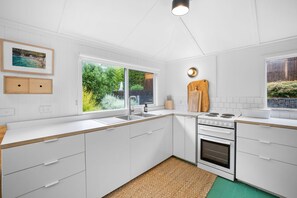 A modern kitchen with white cabinetry, a built-in oven, and a large window offering a view of greenery.