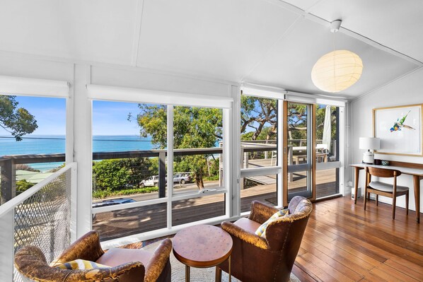 A spacious room with large windows offering a view of the sea and greenery.
