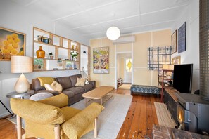 A living room with a sofa, armchairs, a coffee table, a fireplace, and a television.
