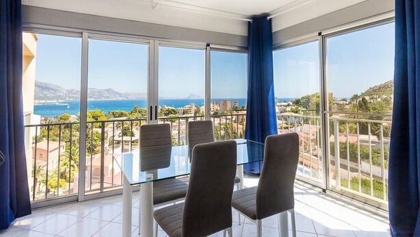 A balcony with a glass table and chairs, offering a view of the sea and surrounding buildings. - VIEWS OF THE BAY (l'Alfàs del Pi)