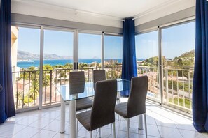 A balcony with a glass table and chairs, offering a view of the sea and surrounding buildings. - VIEWS OF THE BAY (l'Alfàs del Pi)