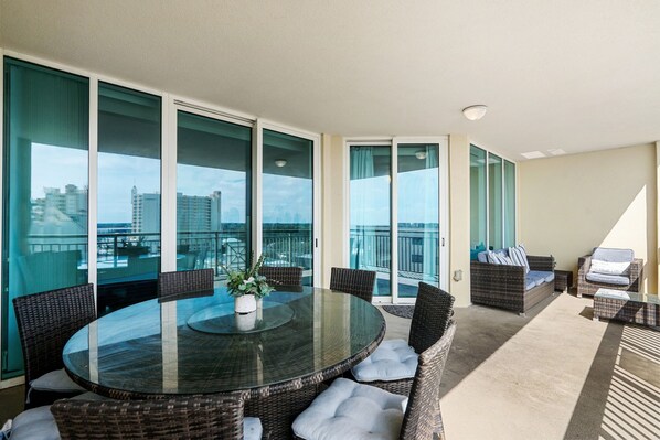 A balcony with a round glass table, wicker chairs, and a sofa.