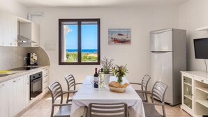 Une cuisine équipée d’une table à manger pour deux personnes, d’un réfrigérateur et d’un téléviseur.