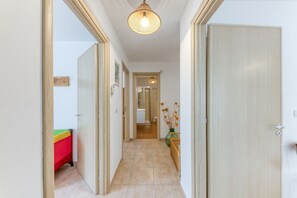 En hall med en trädörr, en lampa och ett klinkergolv.