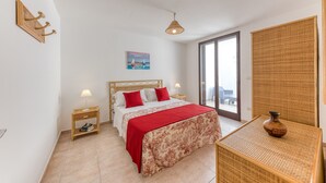 Une chambre à coucher avec un lit, des tables de chevet, une lampe, une fenêtre et une vue.