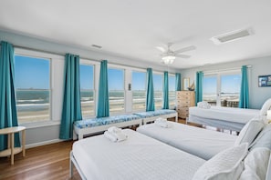 Une chambre d’hôtel avec deux lits, un banc donnant sur un beau paysage, une petite table et une commode.