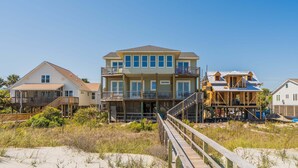 Une propriété située en bord de mer, avec plusieurs niveaux, une terrasse en bois et un ciel dégagé.