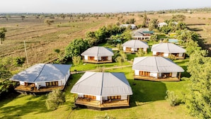 A cluster of cabins with metal roofs, surrounded by lush greenery and fields. - Moyoni Airport Lodge (Arusha)