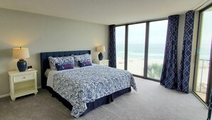 Un dormitorio con una cama grande, dos mesitas de noche y vistas a la playa.