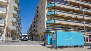 Een meerhoog gebouw met balkons, een straat ervoor en een bord met 'Ajuntament de Calafell'.