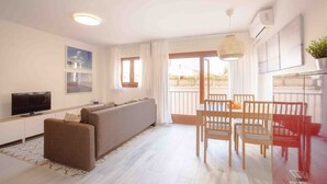 Een moderne woonkamer met een bank, televisie en een eethoek met stoelen en een tafel.