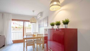 Een moderne woonkamer met een eethoek, een rode kast en twee potplanten.
