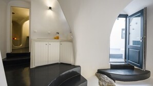 Un interior moderno con área de cocina, una escalera que lleva a un balcón y una puerta al exterior.