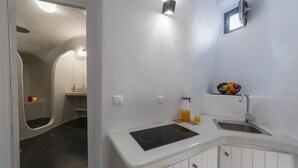 Una cocina compacta con estufa integrada, un lavamanos y un frutero pequeño en la encimera.