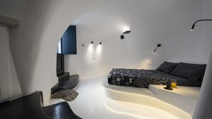 Un dormitorio moderno y minimalista con una cama curva, iluminación empotrada y un televisor montado en la pared.