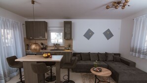 A modern kitchen with a dining area, a sofa, and a small side table. - Apartments PiiP-ni-More (Vodice)