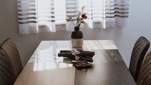 A dining table with a vase of flowers, a stack of folded towels, and a tray of coins. - Apartments PiiP-ni-More (Vodice)