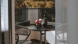 A balcony with a table, a wicker chair, a bottle of wine, and a glass. - Apartments PiiP-ni-More (Vodice)