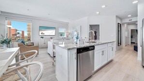 A modern kitchen with white cabinetry, a built-in dishwasher, and a large island with a sink.
