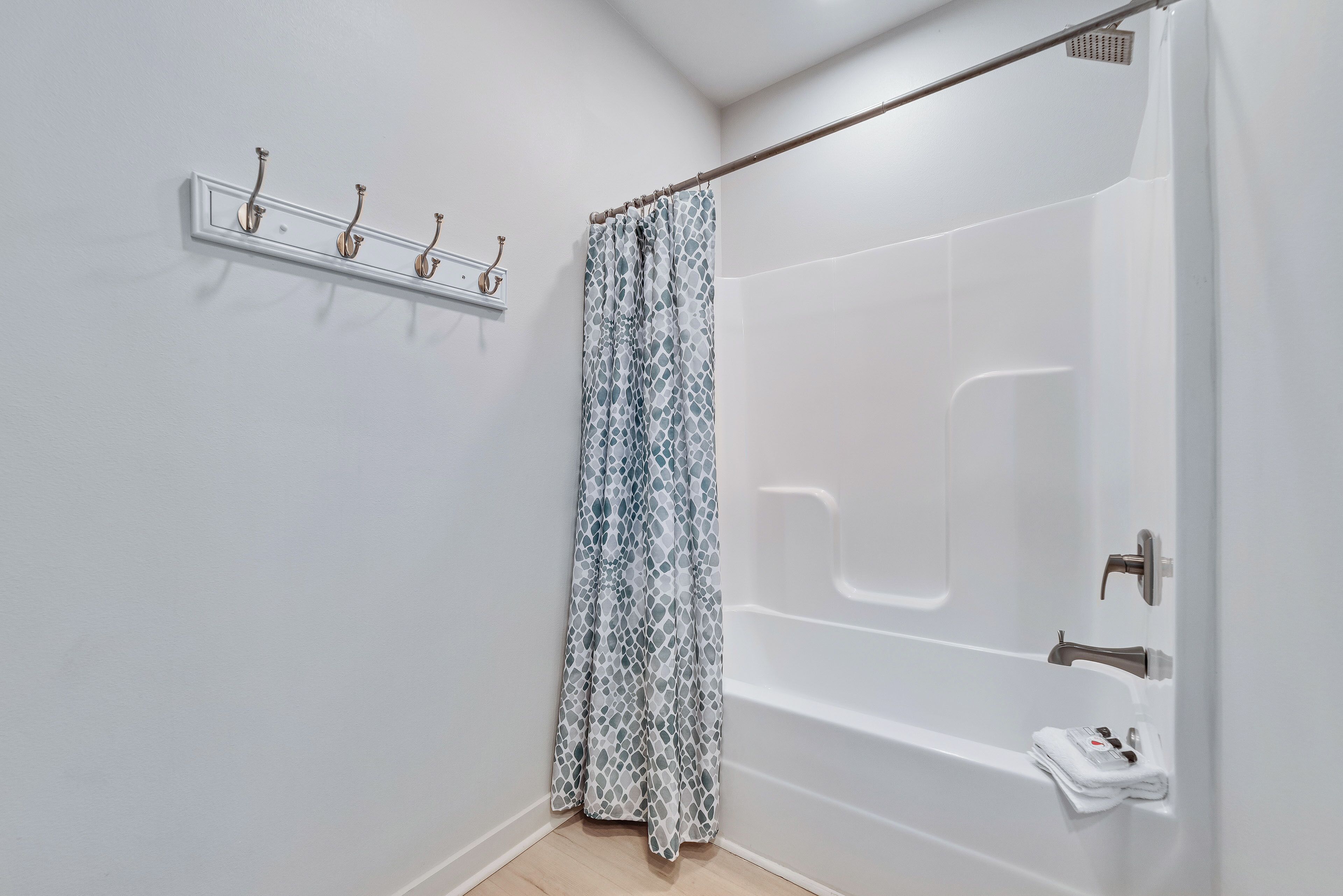 A modern bathroom with a shower, a towel rack, and a bathtub.
