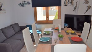A dining area with a wooden table, white chairs, and a grey sofa.
