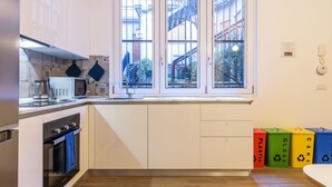 A modern kitchen with white cabinets, a built-in oven, a microwave, and a window with a view of a staircase and greenery outside.