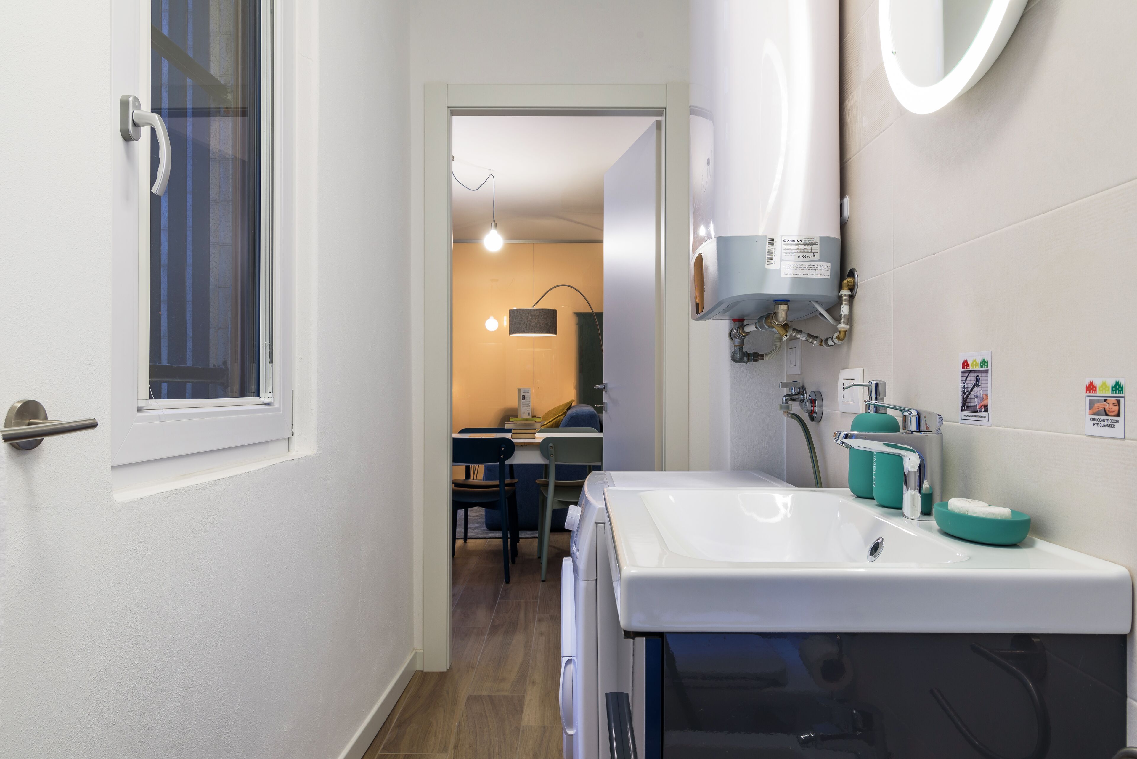A narrow bathroom with a white sink, a mirror, and a towel rack.
