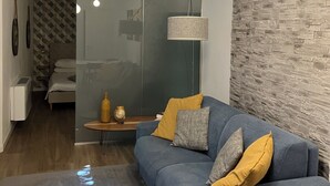 A modern living room with a blue sofa, a glass partition, and a stone-textured wall.