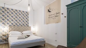 A bedroom with a bed, a wall with a geometric pattern, a cabinet, and a wall with a motivational quote.